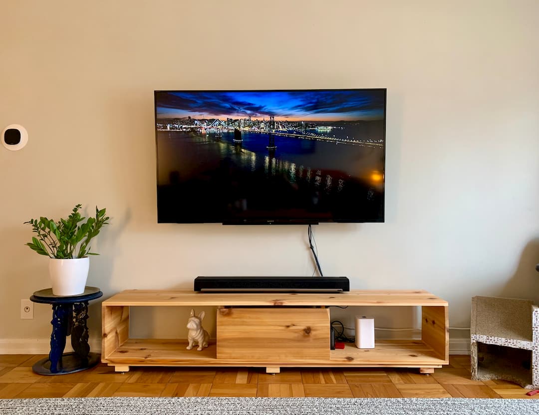Wooden entertainment console below wall-mounted TV.